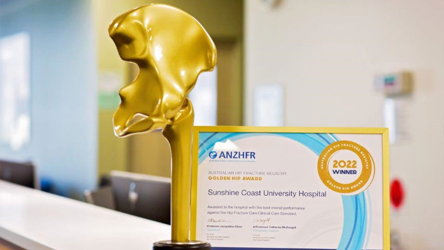 A golden hip bone shaped trophy and framed certificate on a reception desk