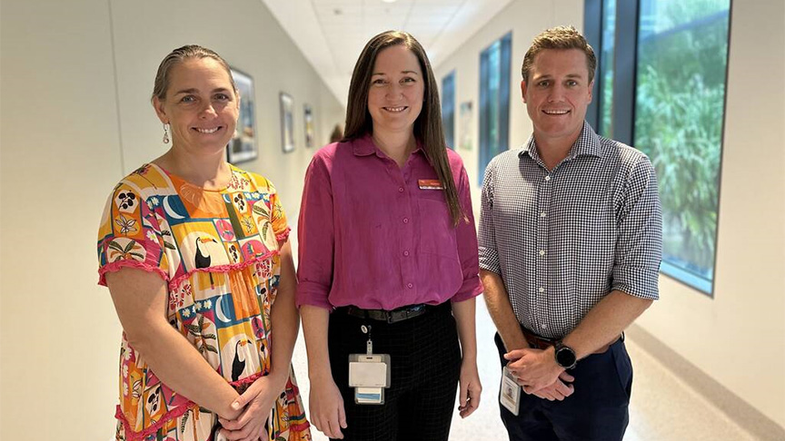 Three people standing in a hospital hallway