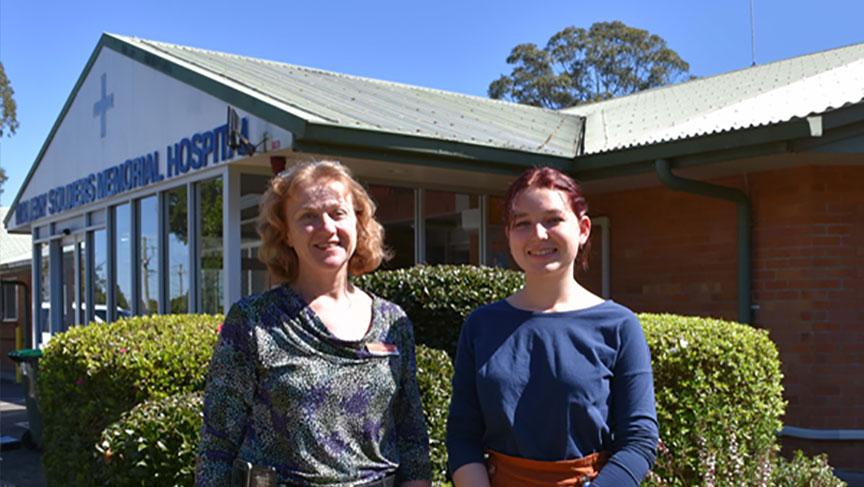 2 people stand outside the front of Maleny Soldier's Memorial Hospital